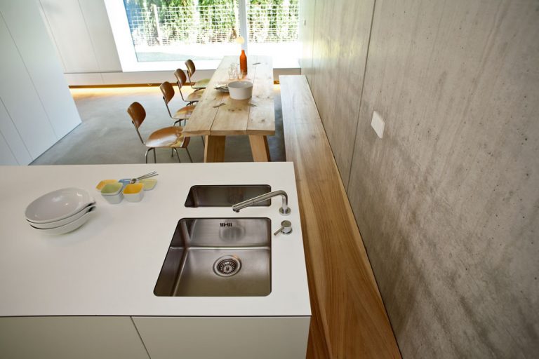Pri kuchynsko-jedálenskej stene je ďalší príklad vstavaného zariadenia – lavica z jelšového dreva. Okno z jedálne je obrátené smerom k susednému pozemku.