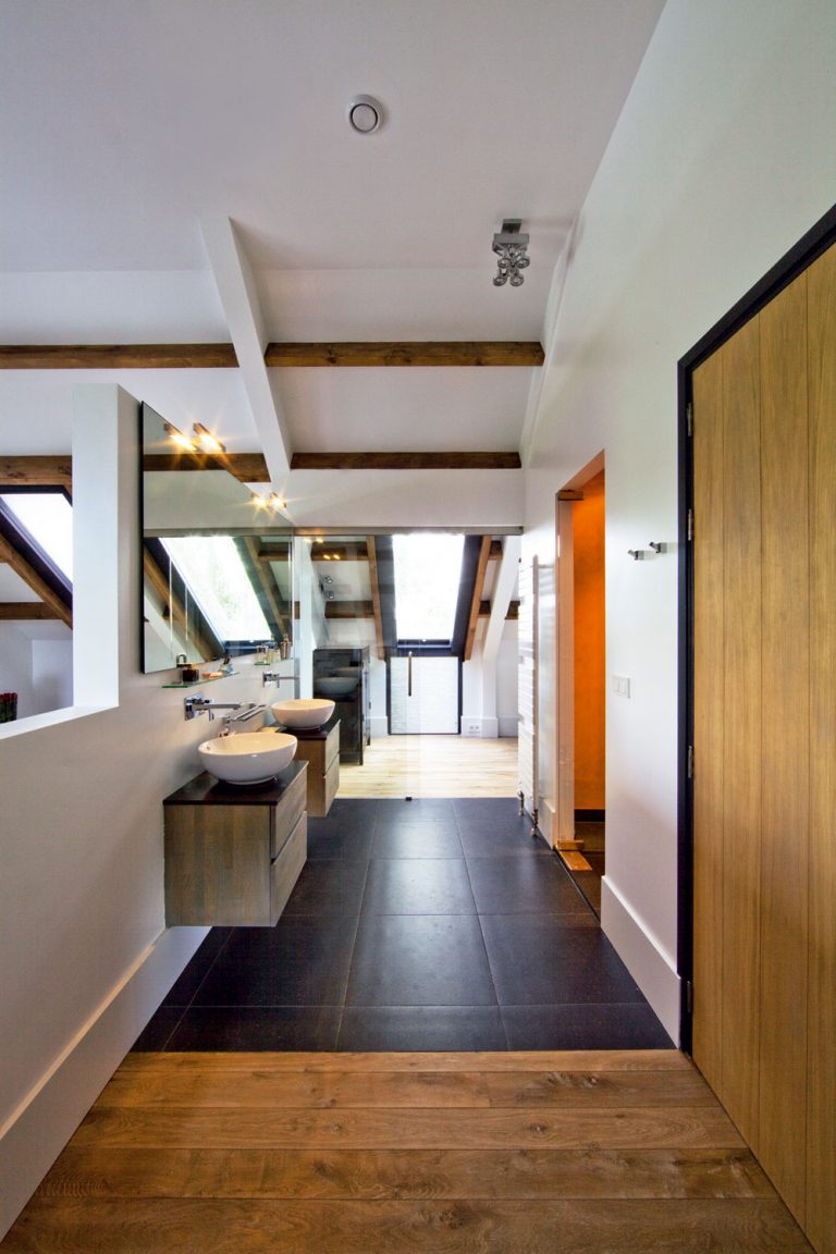 Z kúpeľne pri spálni sa vchádza do šatníka cez podobné sklené dvere, aké sú v kuchyni, smerom do spálne je však kúpeľňa otvorená. Paralelu s kuchyňou vytvára aj nábytok z prírodného dreva a s rovnakým dizajnom. (Umývadlá sú od talianskej firmy Kos.)