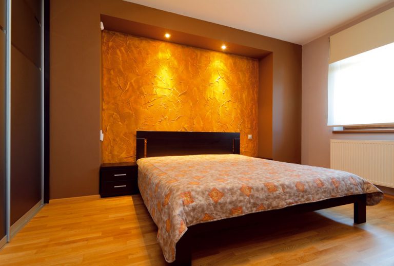 Spálňa je celá ladená do hneda. Dominantne pôsobí stena za čelom manželskej postele, ktorú vytvorili postupným farebným tónovaním nahrubo nanesenej sadrovej omietky.