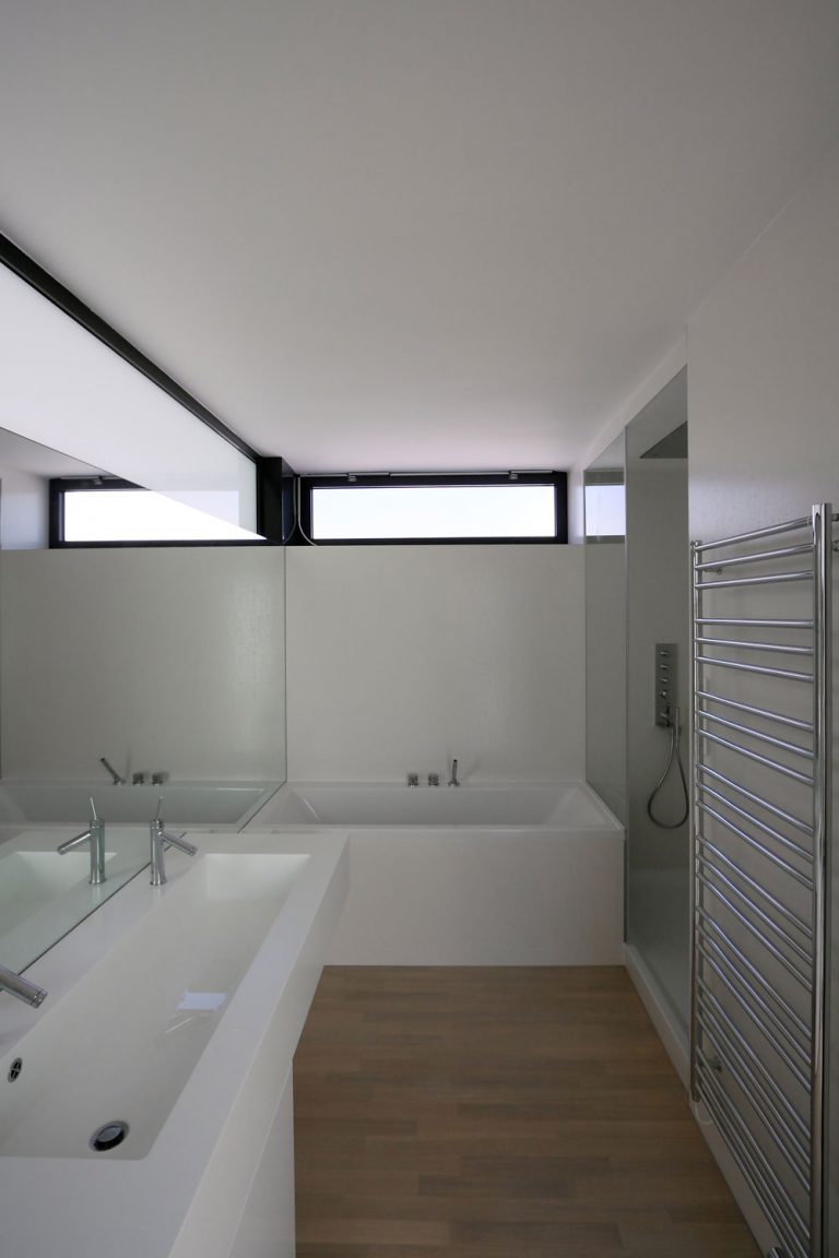 Vrchná časť priečky medzi spálňou a kúpeľňou je presvetlená matným sklom, ktoré dopĺňa prirodzené osvetlenie kúpeľne.