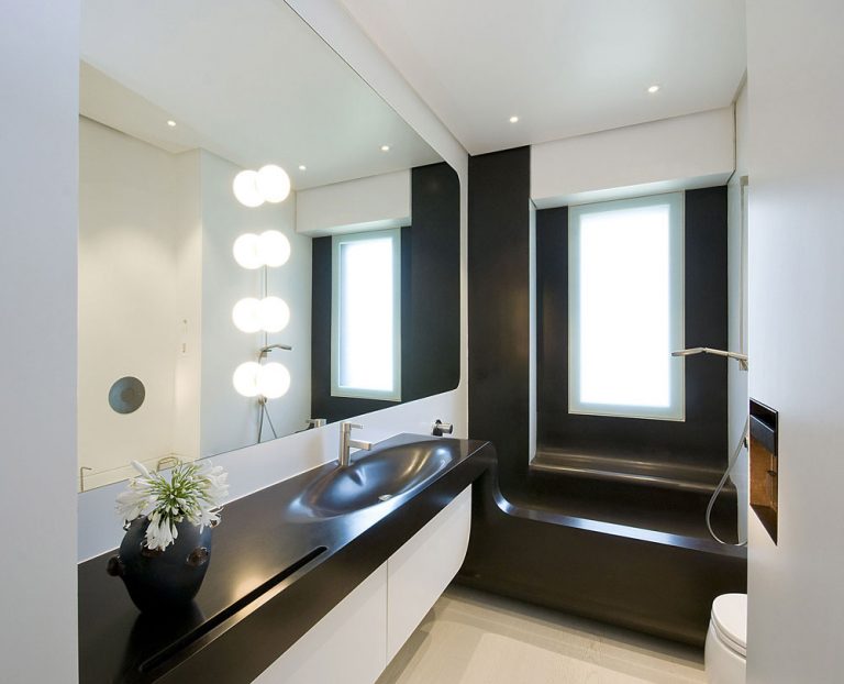 Kúpeľňa v dynamickom bielo-čokoládovom vyhotovení má zaujímavú vaňu, ktorá plní aj funkciu sprchovacieho kúta.