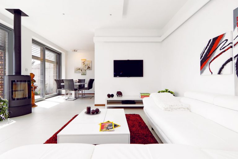 Interiér v bielom, na podlahe obývacej izby odolná dlažba.