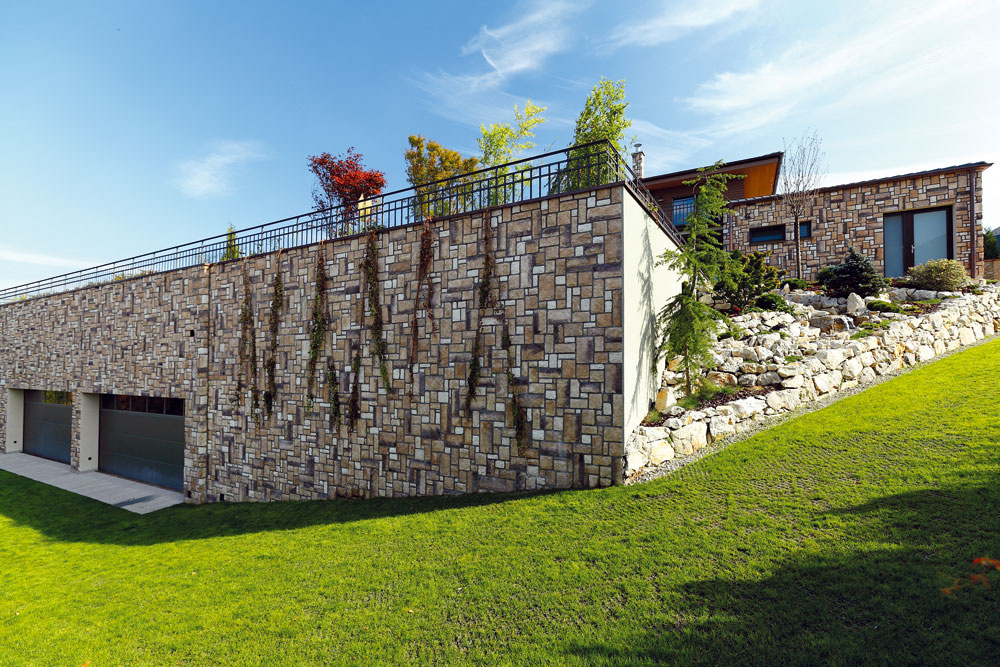 Vysoký oporný múr, ktorý bol potrebný na vytvorenie rovinatej časti záhrady v strmom kopci, časom obrastú popínavé rastliny.
