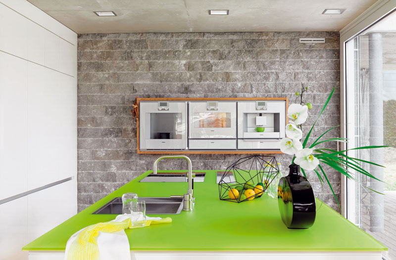 Dekoratívna stena, obložená jurským vápencom, dominuje kuchyni pri pohľade z jedálne. V ergonomickej výške je v nej zabudované trio spotrebičov (Gaggenau) skryté za sklom osadeným v dubovom ráme.