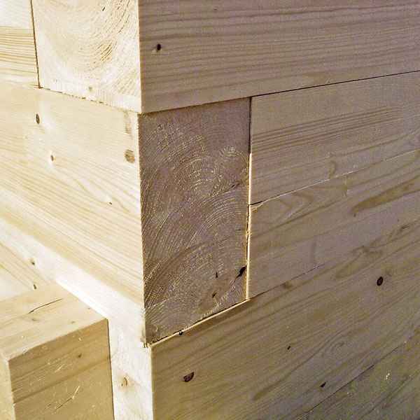 Hranoly sa pri stavbe stien ukladajú jednoducho na seba (na plochu, bez pera a drážky) a fixujú sa tesárskymi skrutkami do dreva. V rohoch sa navzájom kolmé prvky preväzujú (podobný systém väzieb sa využíva aj pri murovaných konštrukciách).