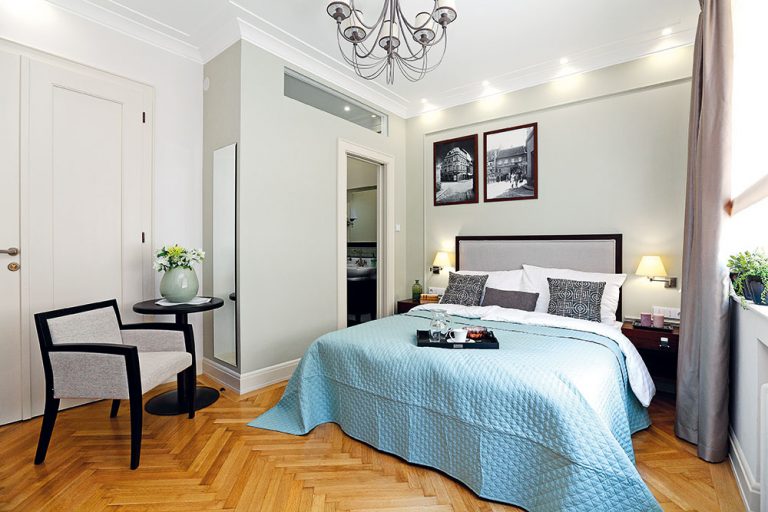 Druhá spálňa – bližšie pri vstupe do bytu – má vlastnú kúpeľňu a môže sa využívať relatívne samostatne. Farebne je ladená do tlmeného odtieňa olivovozelenej v kombinácii so všadeprítomnou béžovou a výraznými čiernymi detailmi. Dominuje jej veľká posteľ s čelom v štýle art déco.