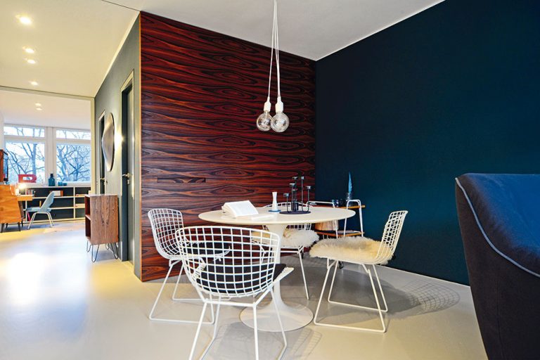 Celý byt je zariadený v štýle dizajnérskej avantgardy päťdesiatych rokov – napríklad jedálenský stôl navrhol Eero Saarinen, stoličky Harry Bertoia (oboje predáva Knoll). Rovnako ako kedysi, aj teraz je na dlážke linoleum (Forbo), pôvodnú tmavočervenú však nahradila svetlosivá (lampy E 27; predáva Muuto).
