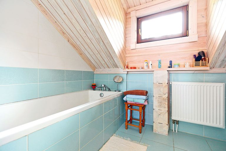 V kúpeľni na poschodí vytvárajú príjemnú atmosféru drevené steny v pokojnej farebnej kombinácii s pastelovomodrým a bielym obkladom.