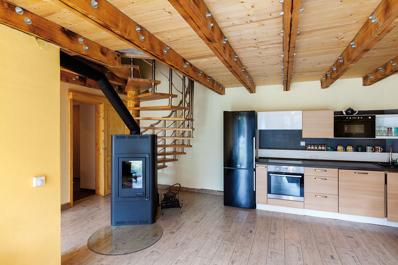 Centrom dispozície je otvorený priestor obývačky spojenej s jedálňou a kuchyňou, z ktorej sa po drevenom schodisku vystupuje  do spální na poschodí.