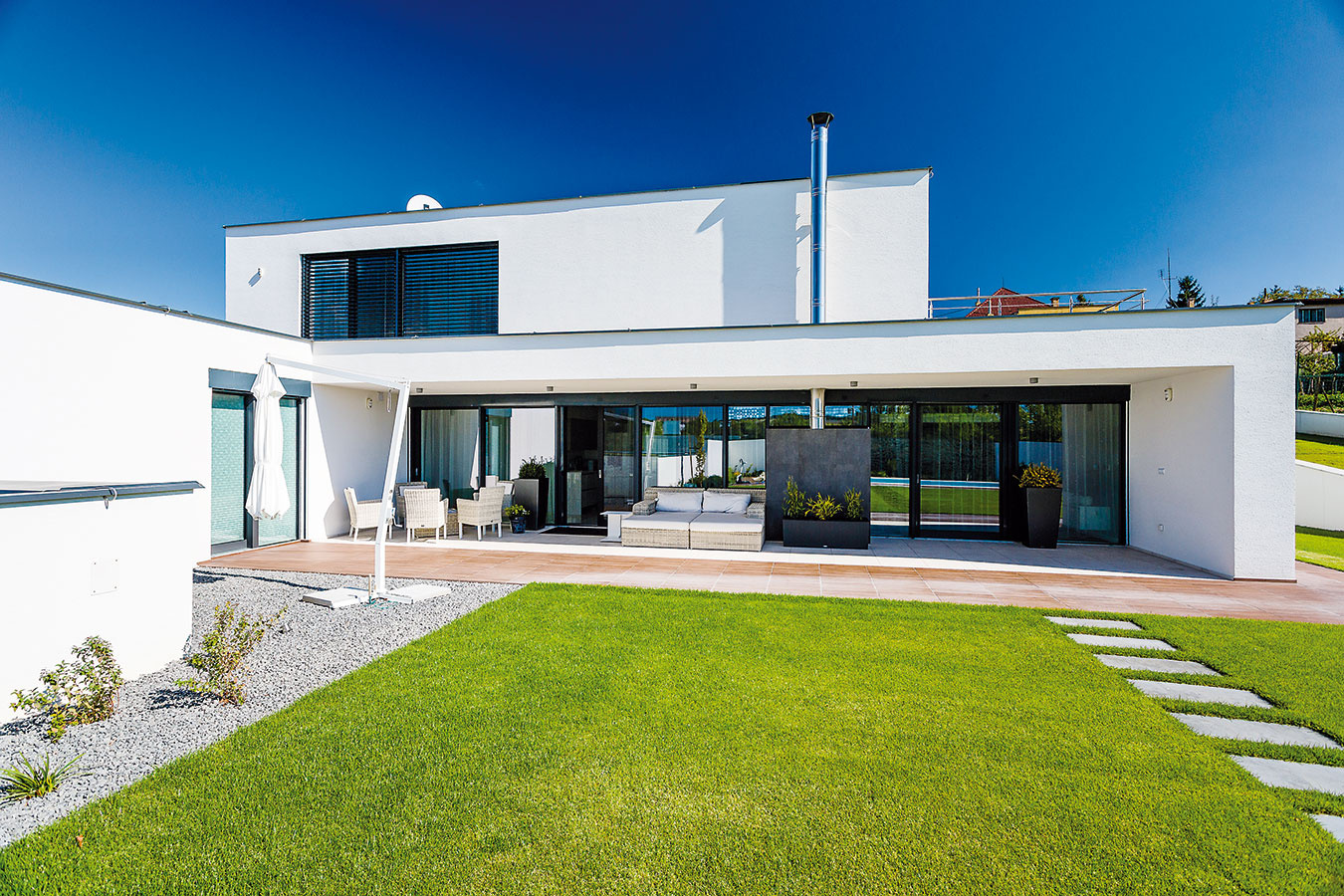S terasou a záhradou spája interiér veľkorysá zasklená stena, ktorá v zime zároveň zabezpečuje dôležité solárne zisky.