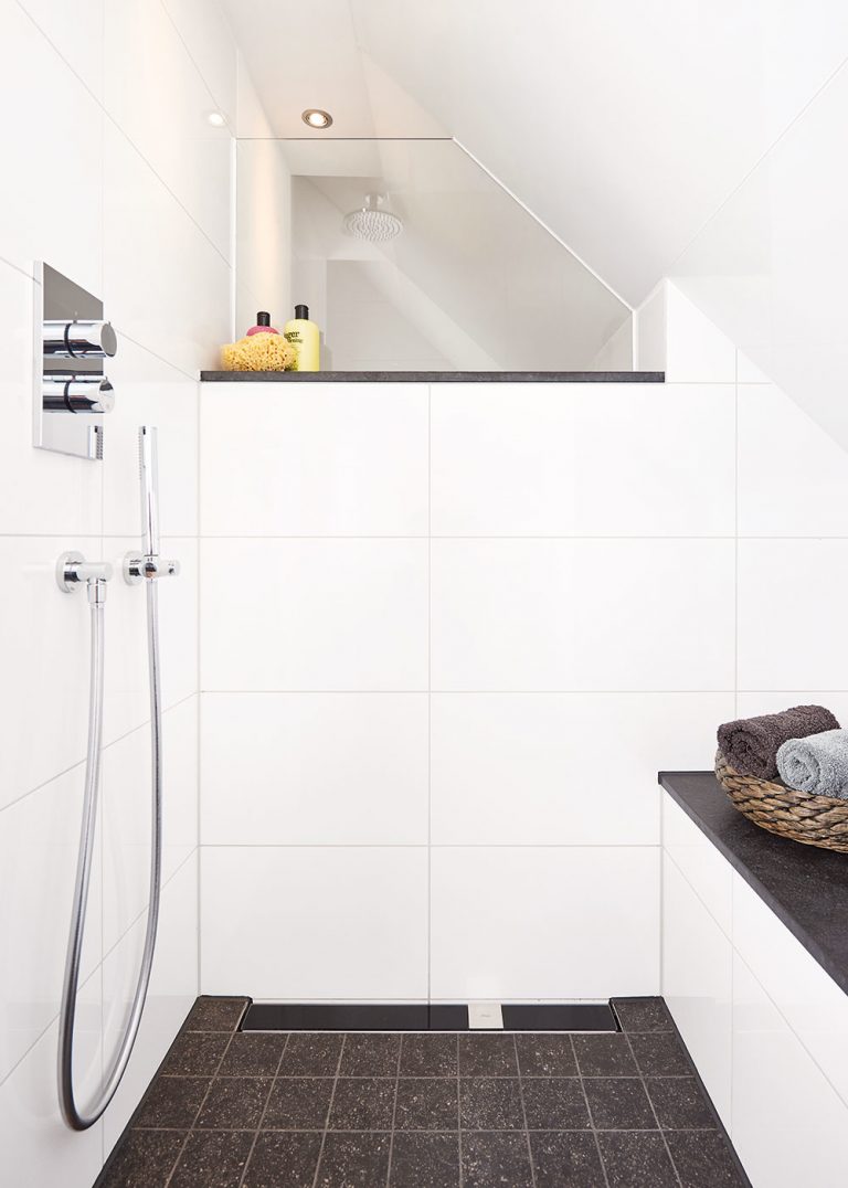 Sprchový kút typu walk-in poskytuje dostatočný priestor a voľnosť pohybu aj v podkrovnej kúpeľni so šikmým stropom. Takéto riešenie navyše kúpeľňu opticky otvorí a vďaka bezprahovému prechodu ho investor ocení aj vo vyššom veku. Jeho súčasťou je aj praktická lavička.