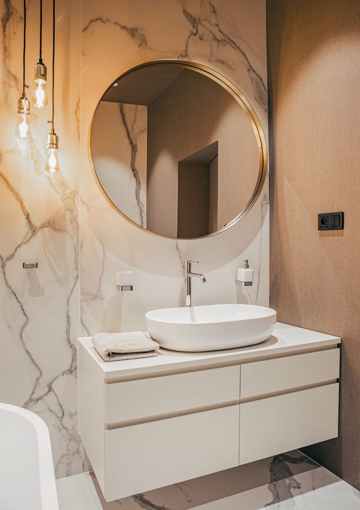 Aj v kúpeľniach sa stretáva pôsobivá kombinácia tapiet a dlažby, ktorá je naozaj všetko, len nie obyčajná. Žiarovky visiace zo stropu sú od značky Arli, zrkadlá od Kare design.
