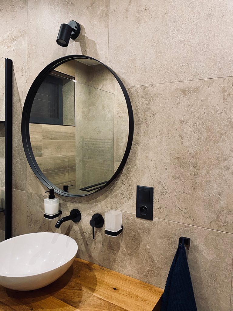 kúpeľňa s okrúhlym zrkadlom a umývadlom