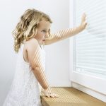 Dievčatko pri okne so žalúziou