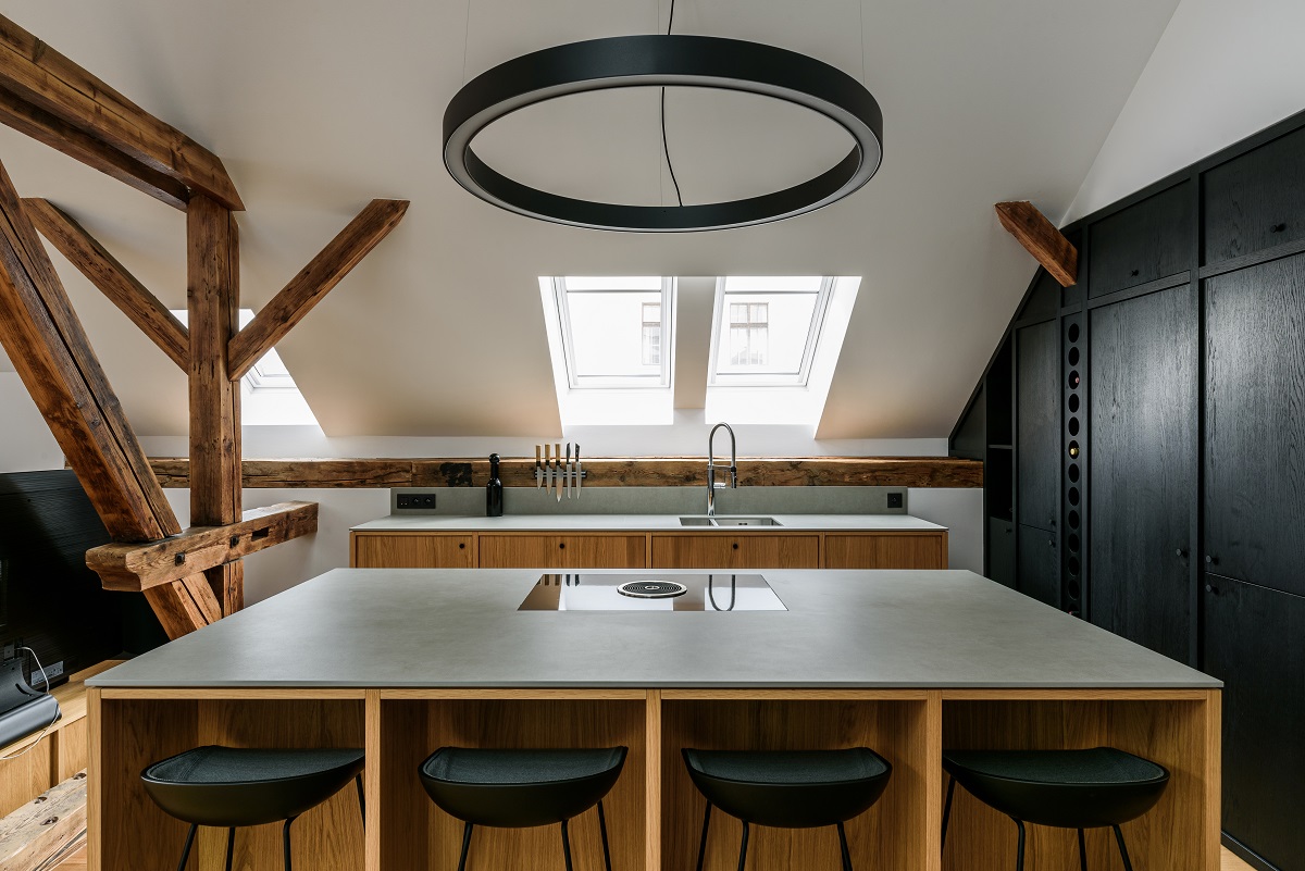 kuchyňa v podkroví s drevenými trámami a čiernou stenou
