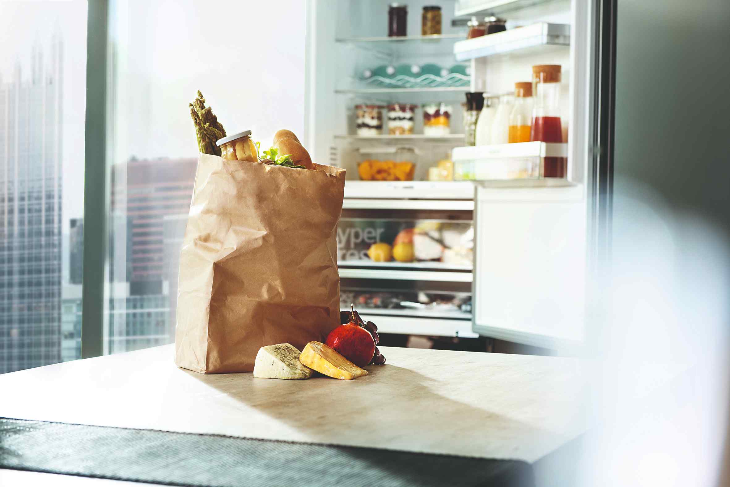 Papierová taška s nákupom pred otvorenou chladničkou