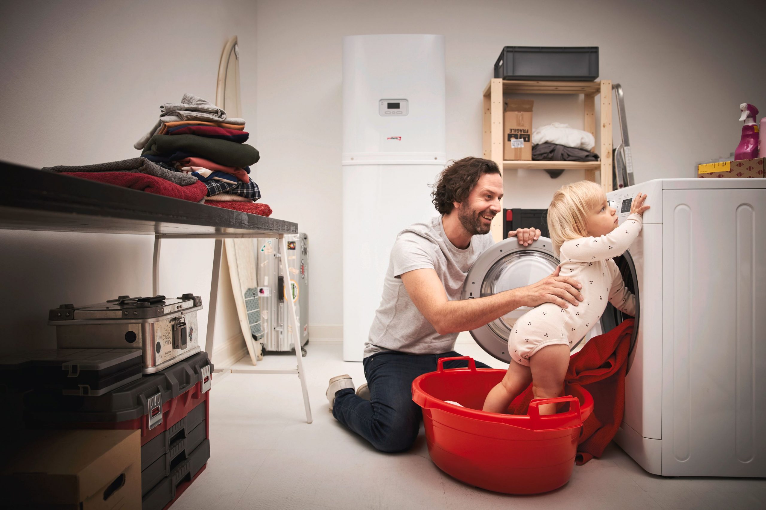 Otec s dieťaťom pri otvorenej práčke v technickej miestnosti