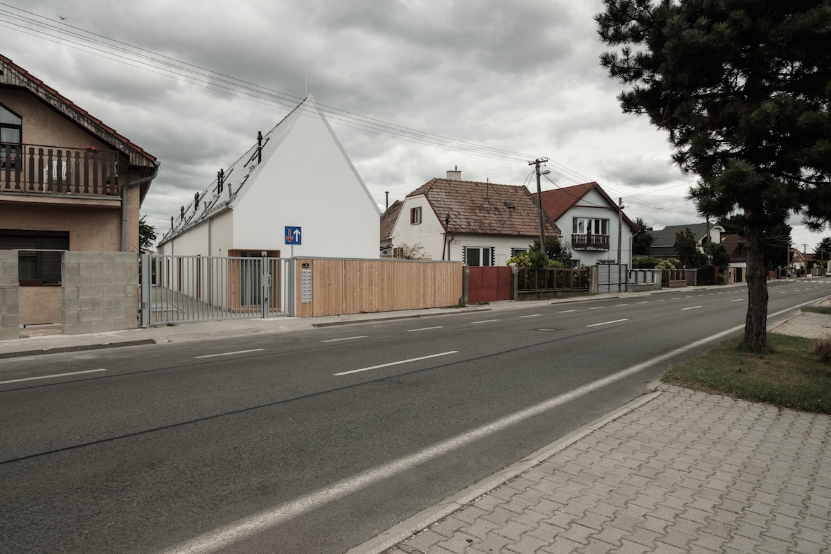 Koncept domu je založený na doplnení tradičného urbanistického kontextu vidieckej zástavby, teda územia so zástavbou pôvodných úzkych a dlhých domov so sedlovou strechou pozdĺžne radených kolmo na hlavnú komunikáciu.