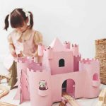 Ružový hrad z krabice a hrajúce sa dievčatko