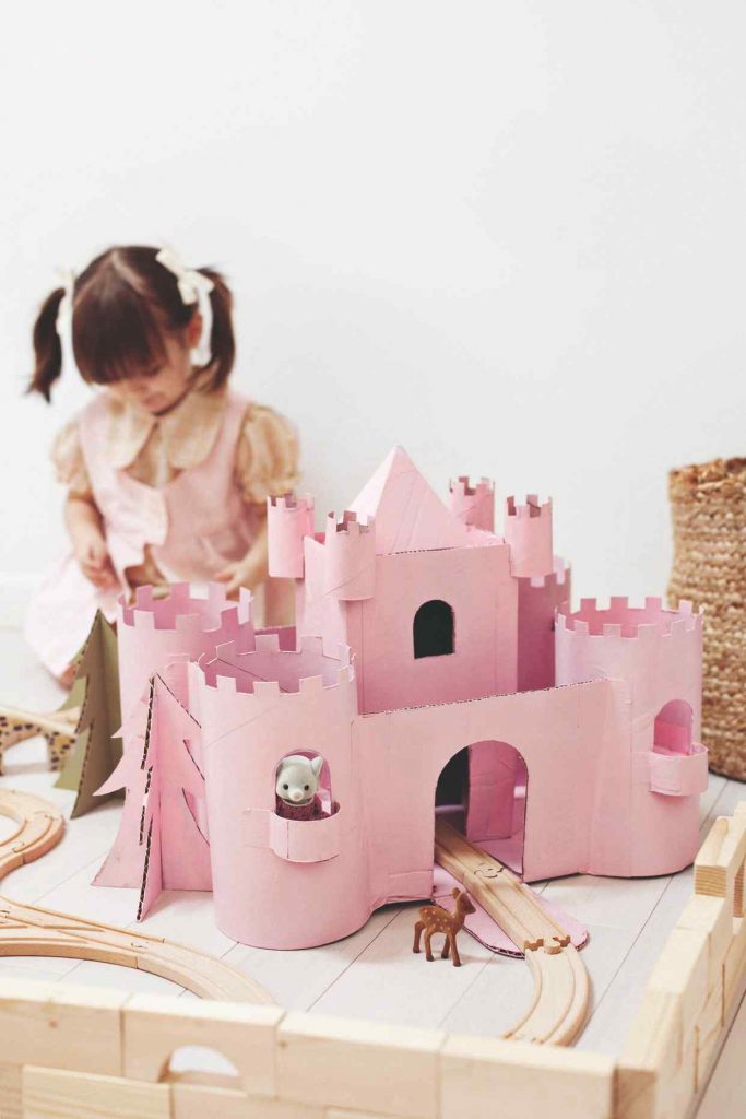 Ružový hrad z krabice a hrajúce sa dievčatko