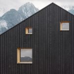 Robustná čierna fasáda s nepravidelnými oknami