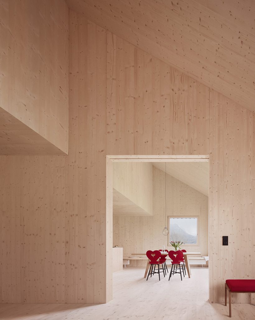Smrekový interiér domu s červenými stoličkami v jedálni