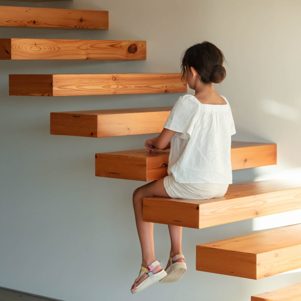 Dievča sedí na drevenom schodisku
