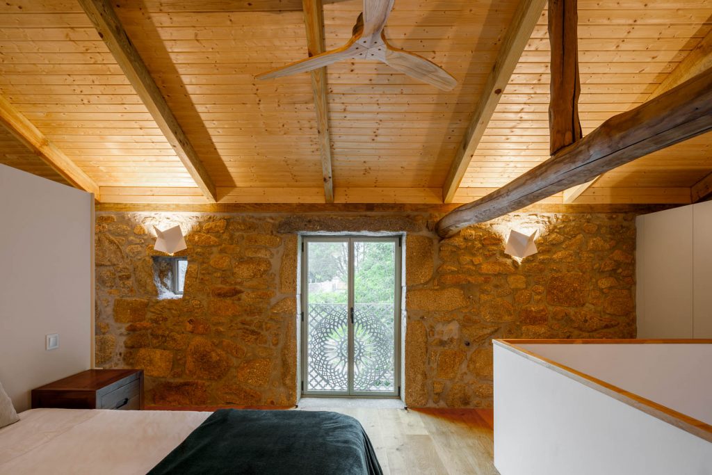 Spálňa s dreveným stropom a kamennou stenou