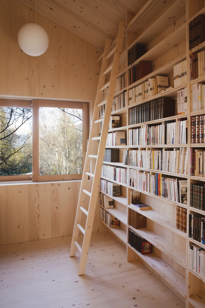 Svetlá drevená knižnica s rebríkom v chate