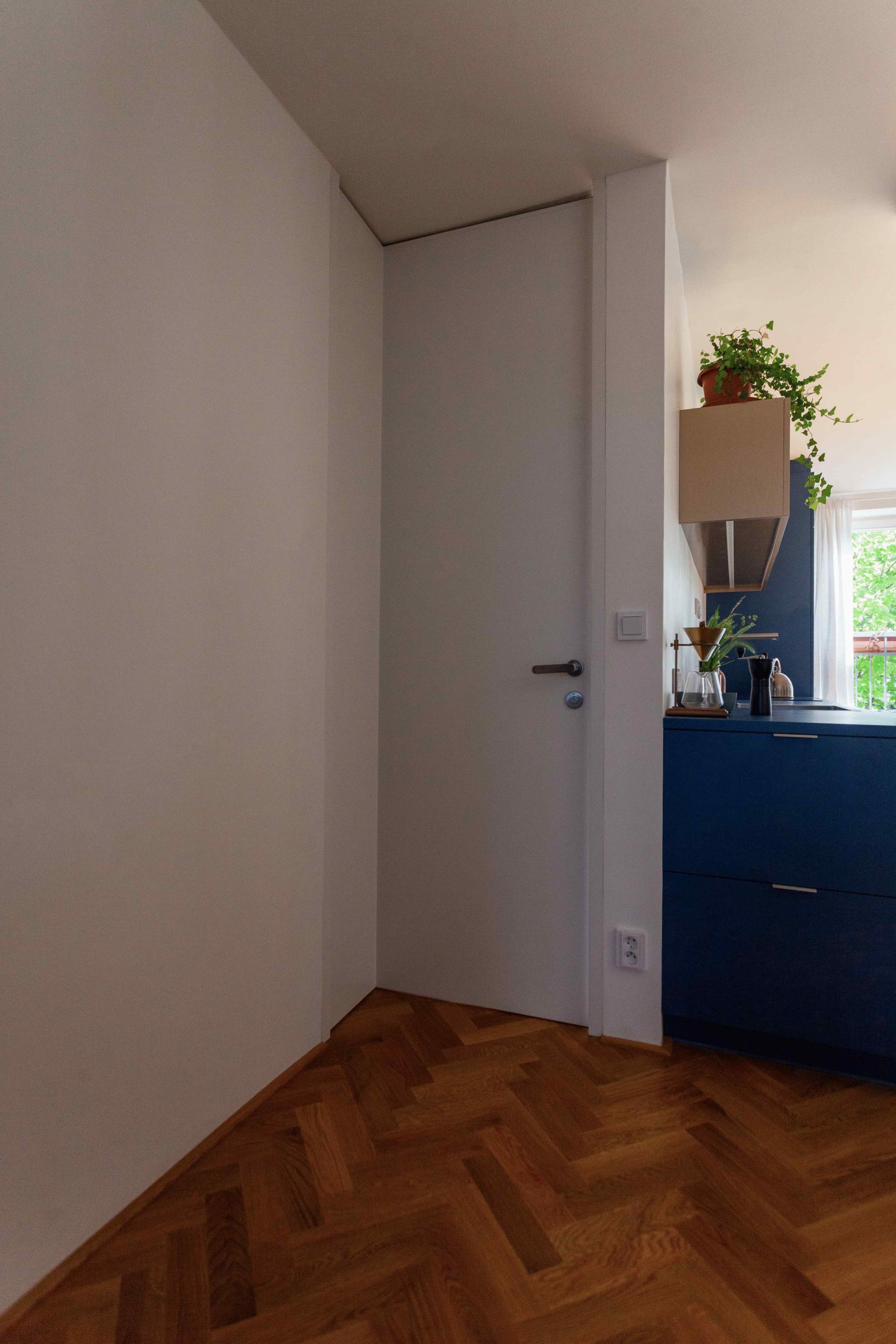 Namiesto šikmej steny, ktorá tu bola pôvodne architekti navrhli špeciálne bezzárubňové dvere v tvare písmena L na celú výšku miestnosti.
