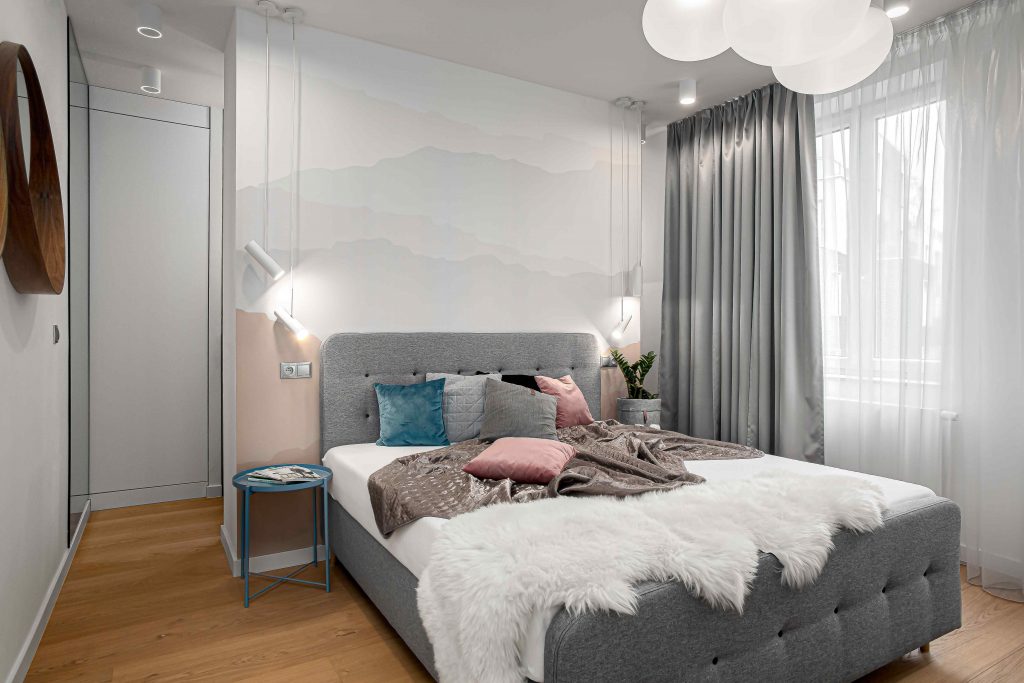 Biela spálňa so sivou čalúnenou posteľou