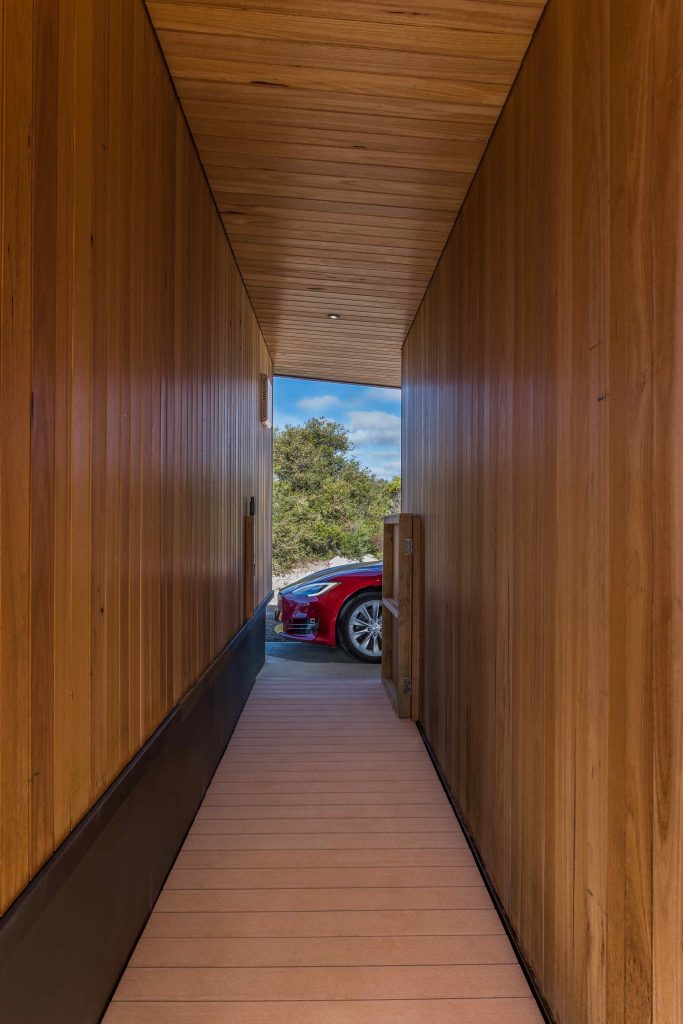 Pohľad cez chodbu s drevenou fasádou na červené auto