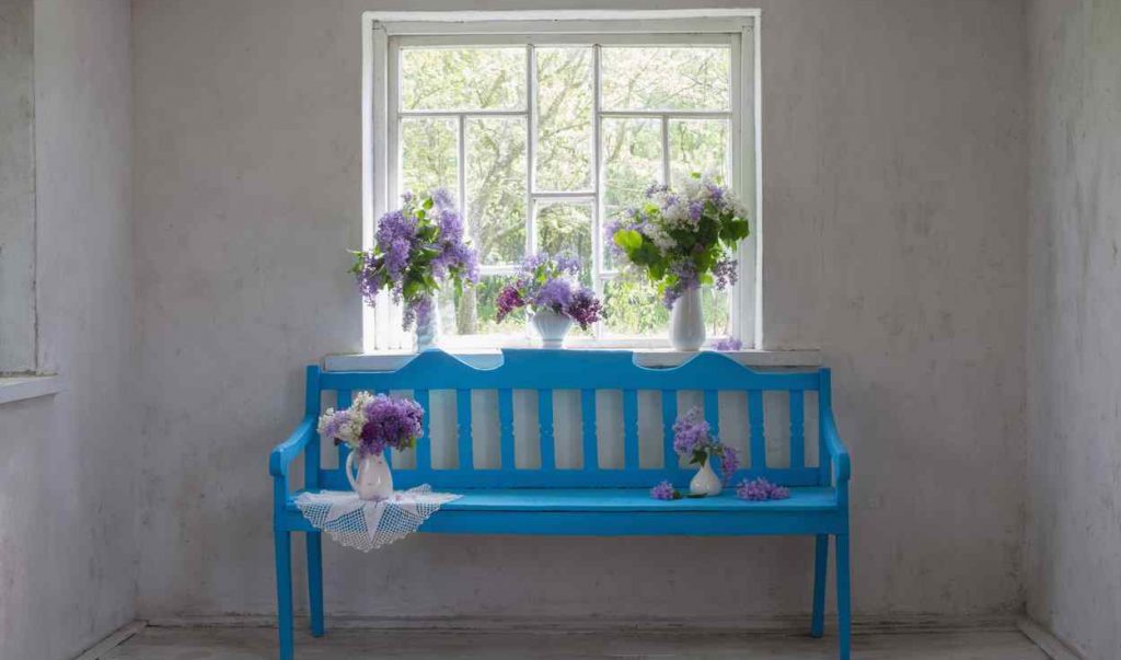 Modrá lavica pred oknom s kvetmi