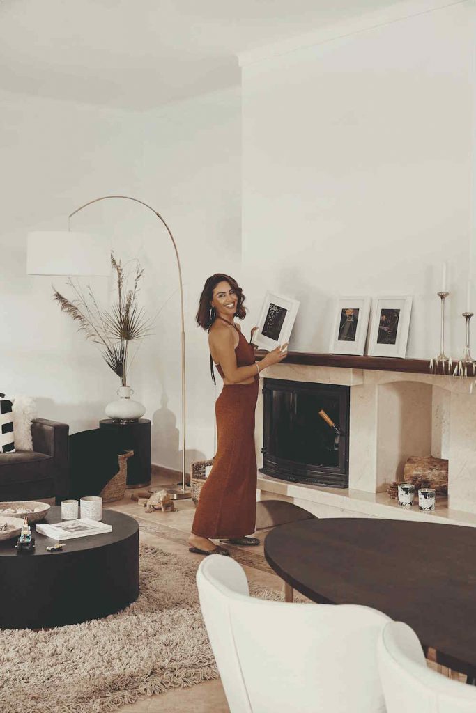 Žena pri krbe v obývačke držiaca rám s fotografiou
