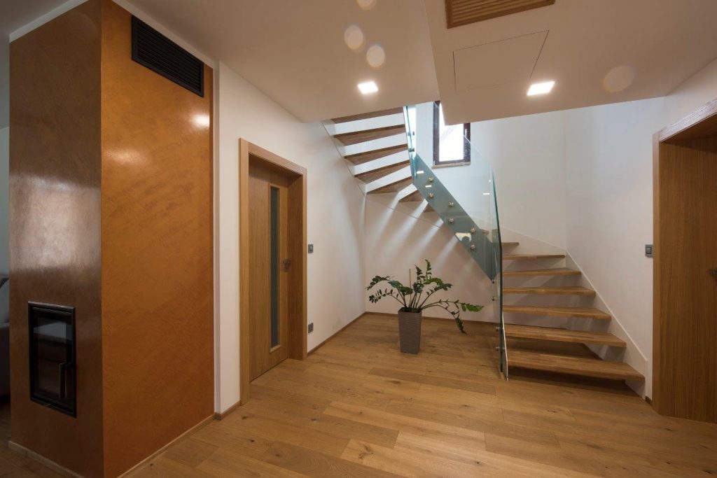 Interiér domu s drevenou podlahou, schodišťom a dverami