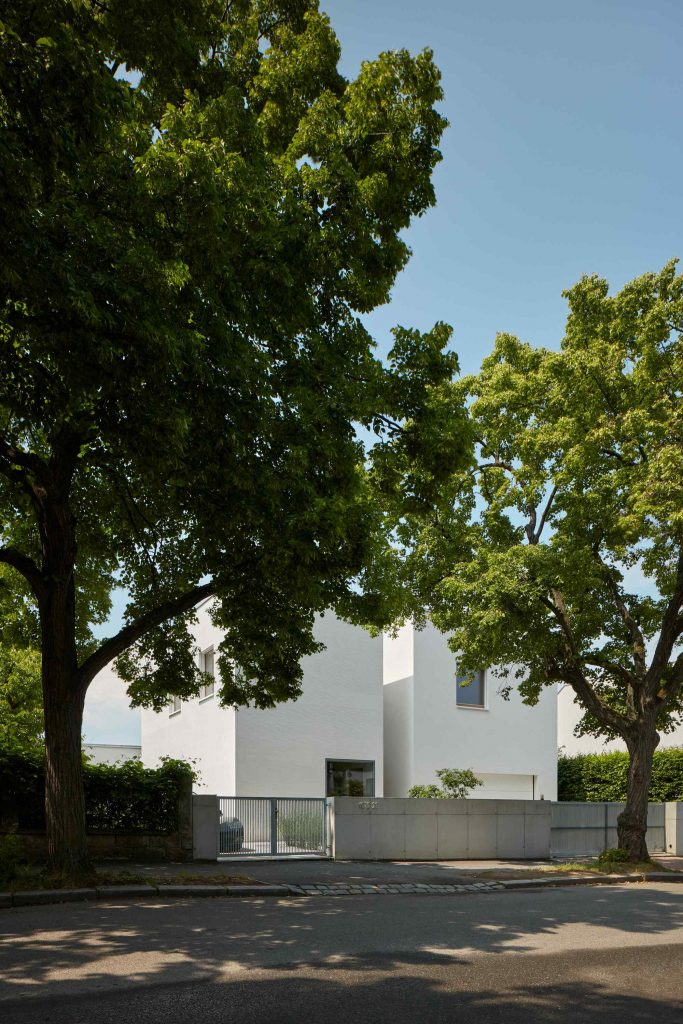 Hranatý biely dom za stromami