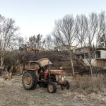 Traktor na pozemku v pozadí hranatý rodinný dom