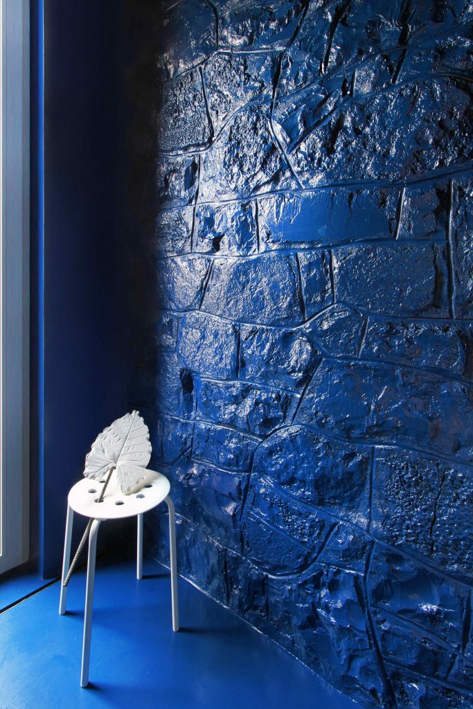 Modrá lesklá živica na stene biely stolček