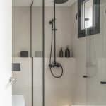 Biela kúpeľňa so sprchovacím kútom v čiernej