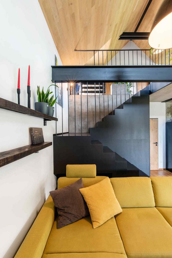 Čierne minimalistické schodisko v obývačke so žltým gaučom