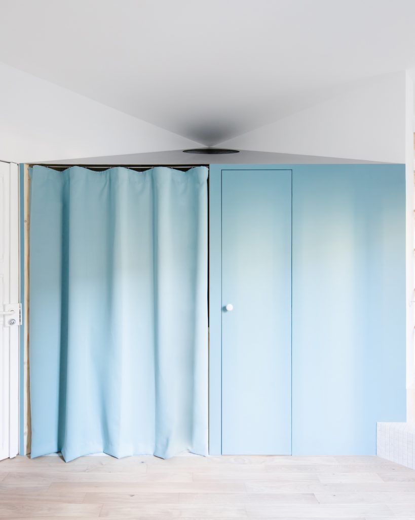 Modrý záves a stena s rovnakými dverami v malom byte