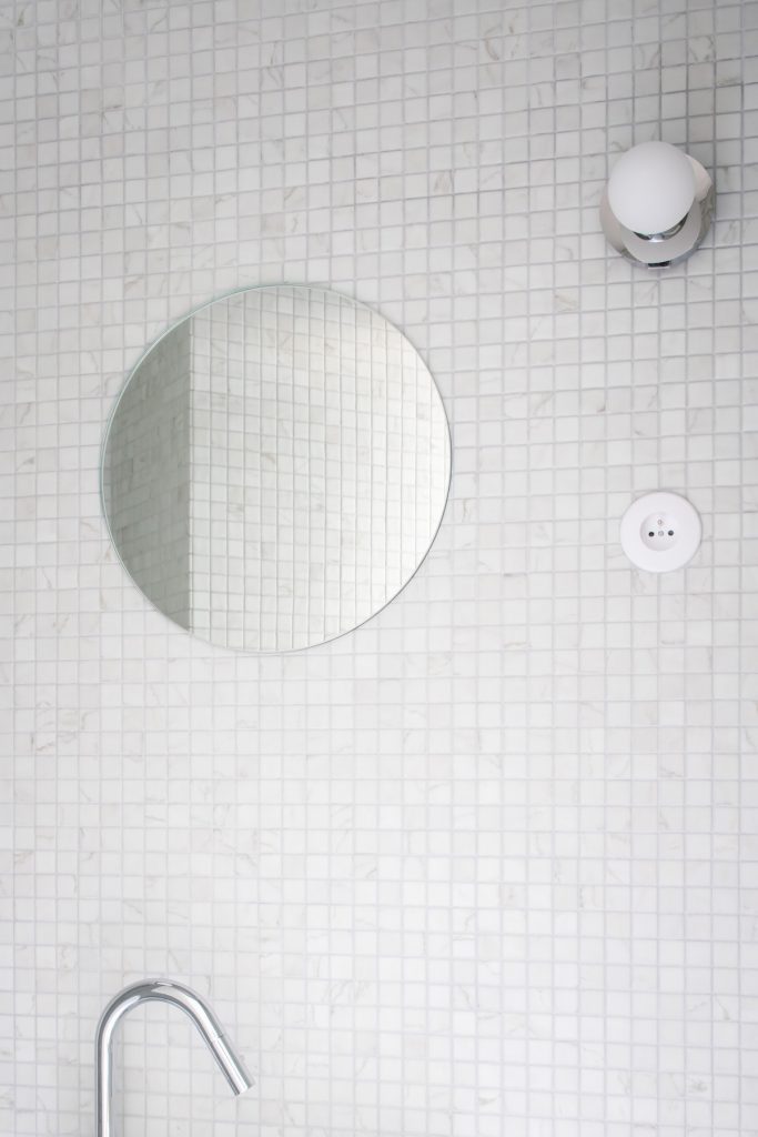 Okrúhle zrkadlo na bielej mozaike v kúpeľni