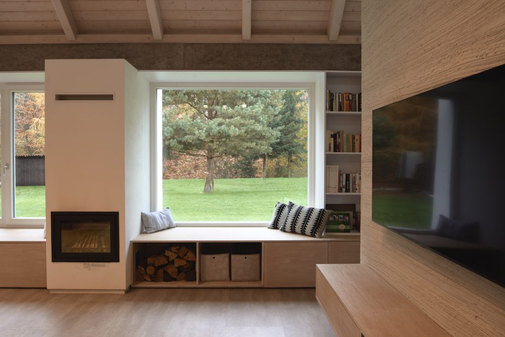 Obývačka s veľkými oknami so sedením a s výhľadom do lesa