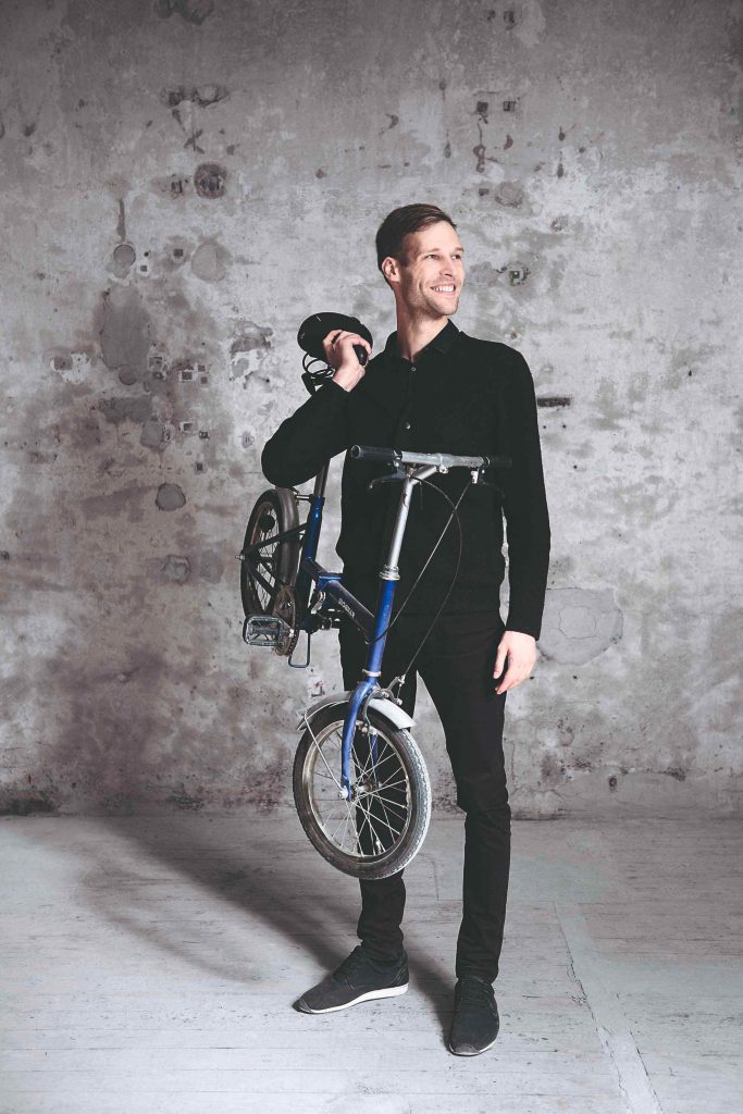Muž smejúci sa a držiaci skladací bicykel