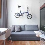 Sivý gauč nad ktorým je zavesený mestský bicykel