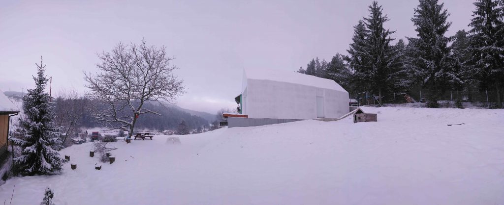 Celobiely dom v horách vo svahu v zime