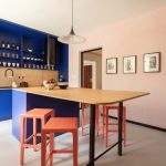 Výrazná modrá kuchyňa so svetlým drevom a červené stoličky