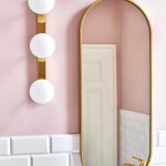 Zlaté zrkadlo a svietidlo na ružovej stene v kúpeľni
