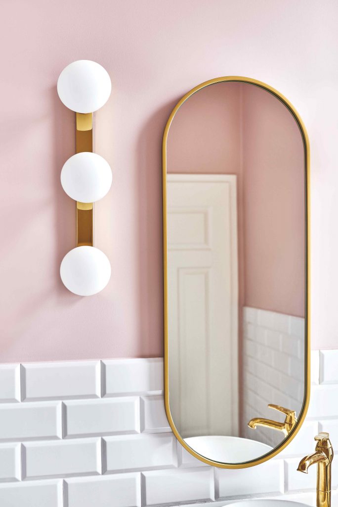 Zlaté zrkadlo a svietidlo na ružovej stene v kúpeľni