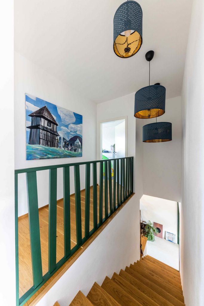 Zelené schodisko s modrými lampami a obrazom